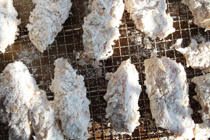 chicken dredged in flour on a tray before frying