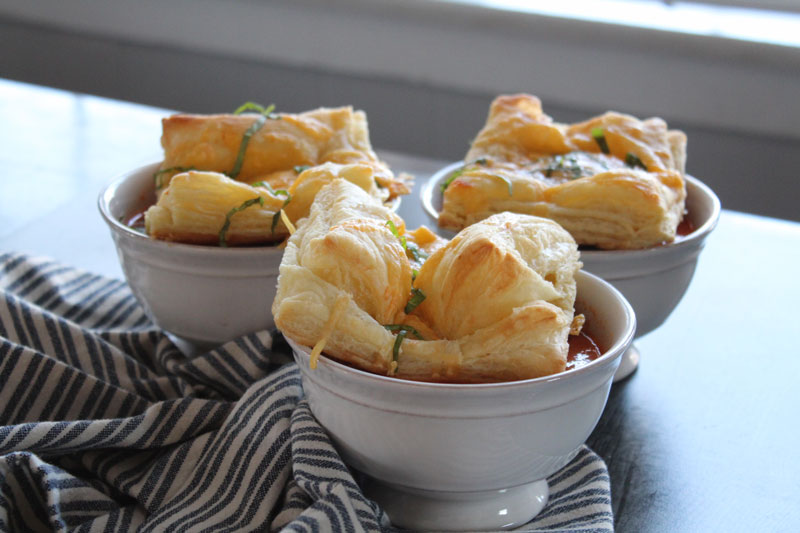 Three bowls of sun dried tomato tortellini soup with cheese pastries on top