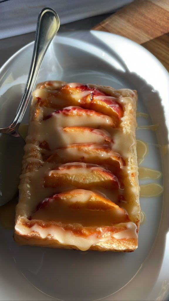 A close up of a peach pastry with glaze on top