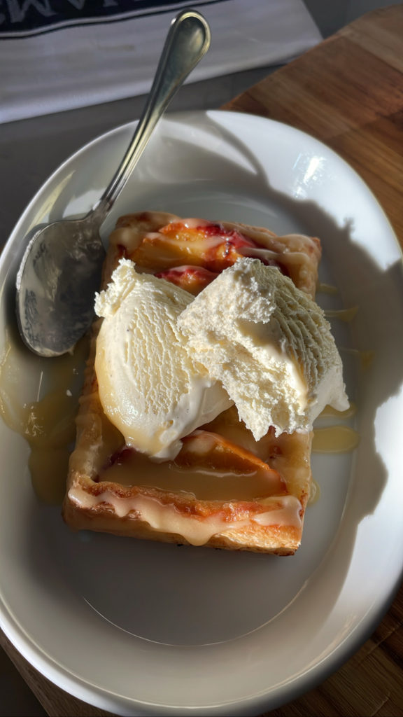 A peach pastry with bourbon hard sauce, and a scoop of ice cream on top